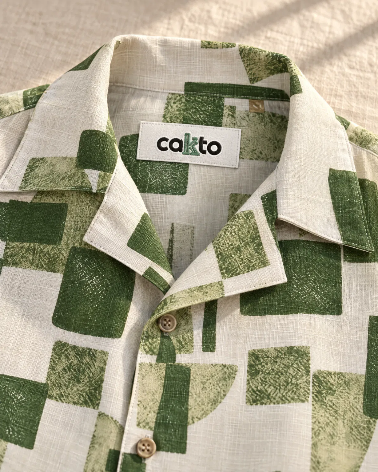 Detalle del estampado, el cuello y la etiqueta Cakto de la camisa duna verde