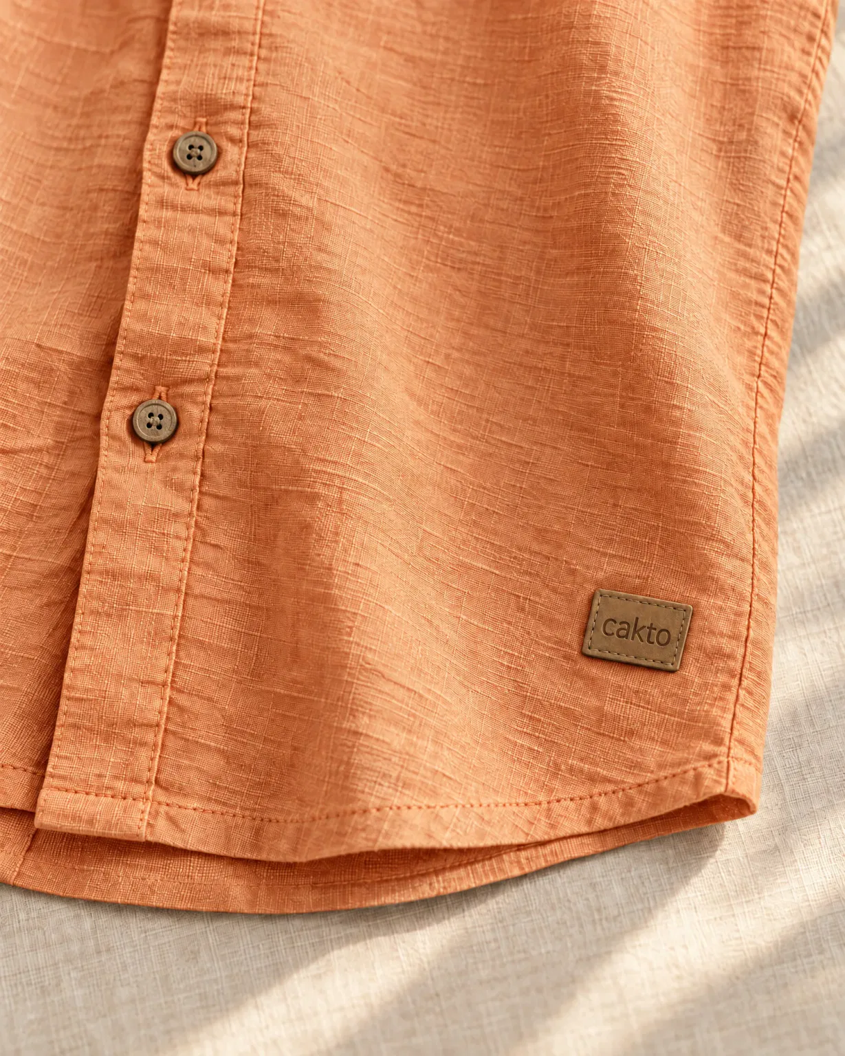 Detalle de la textura, los botones y el parche de cuero Cakto de la camisa texturizada anaranjada