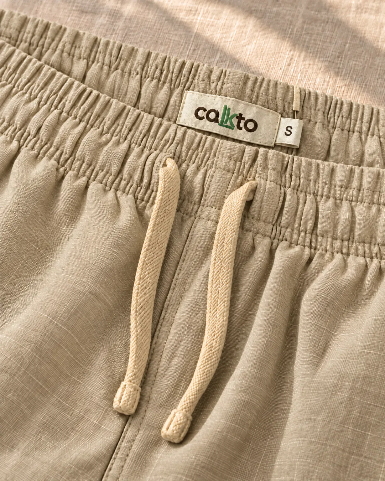 Detalle de la pretina con cordón y marquilla Cakto de la bermuda de lino beige