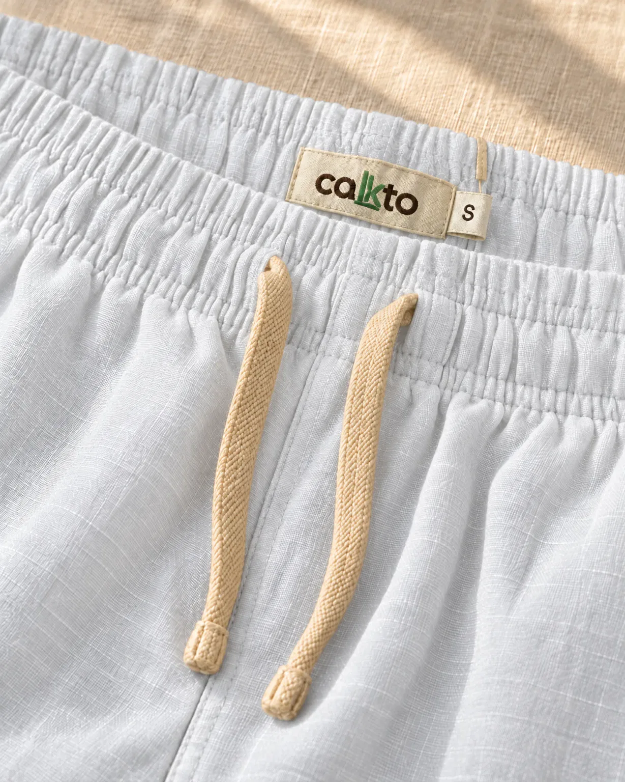Detalle de la pretina con cordón y marquilla Cakto de la bermuda de lino blanca