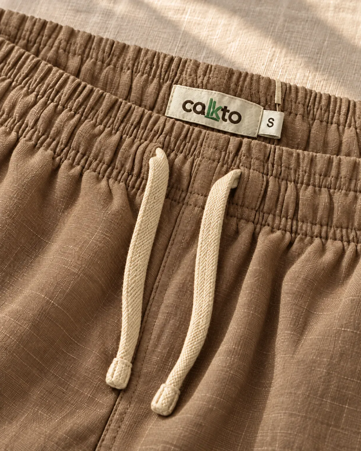 Detalle de la pretina con cordón y marquilla Cakto de la bermuda de lino café