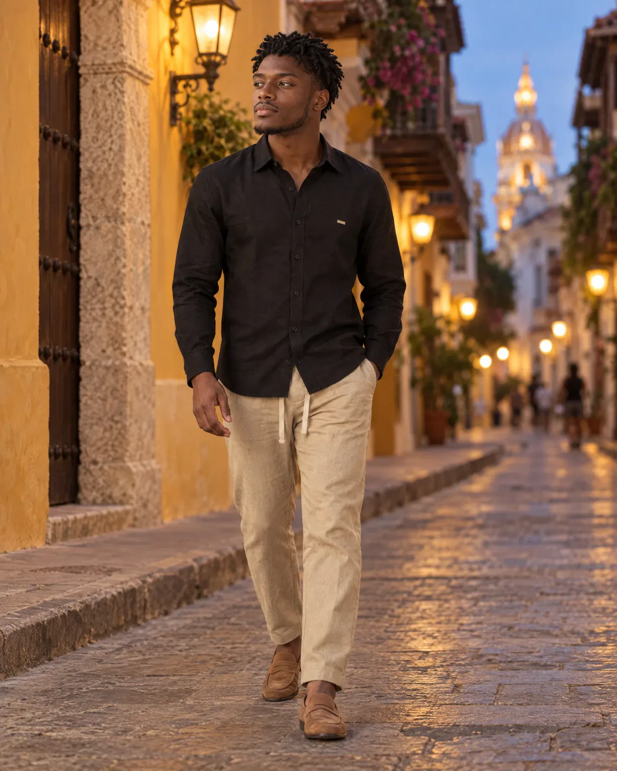 Hombre con camisa manga larga negra con pantalón de lino beige en una calle de Cartagena de noche