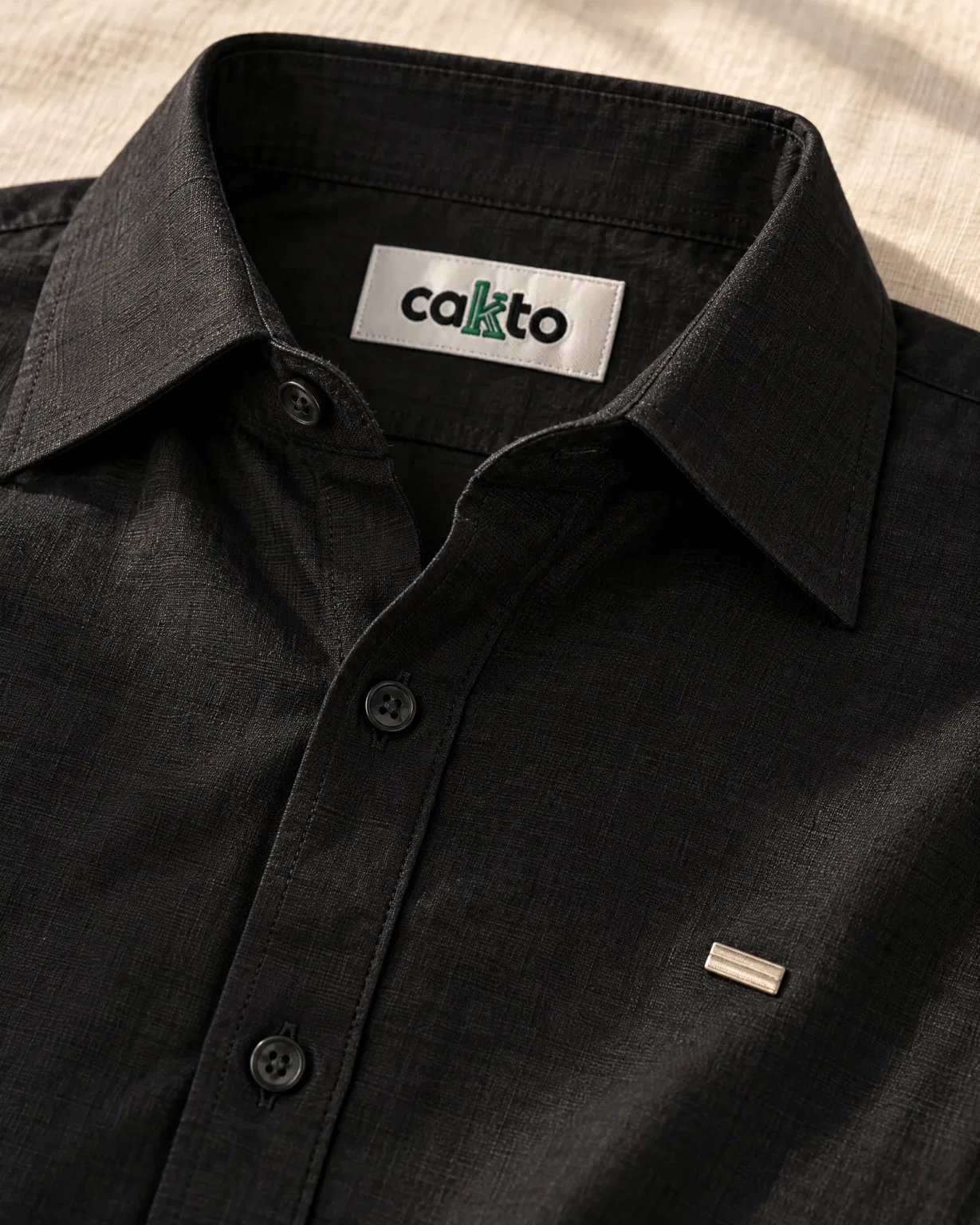 Detalle del cuello, la tela y la etiqueta Cakto de la camisa manga larga negra