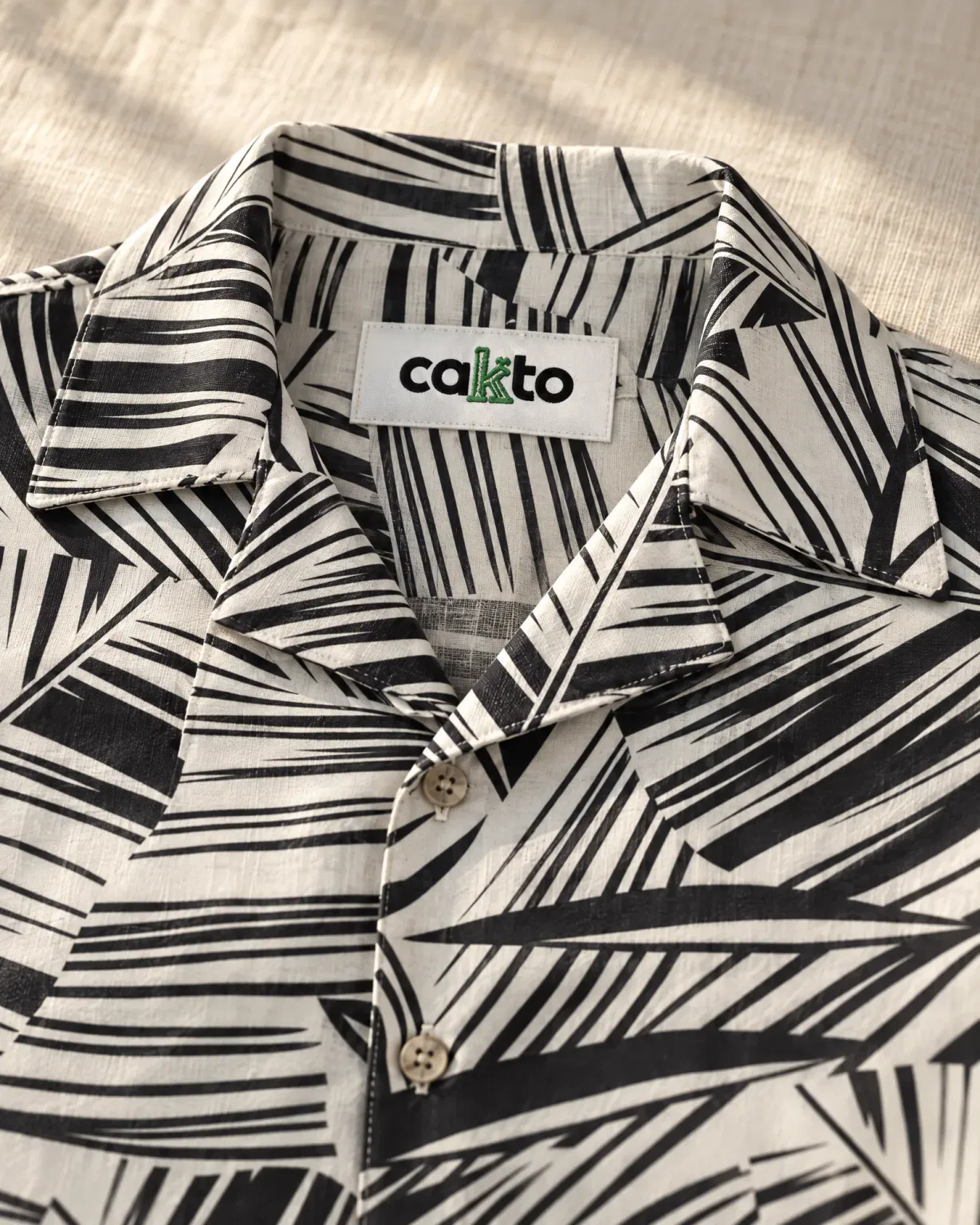 Detalle del estampado, el cuello y la etiqueta Cakto de la camisa palmera