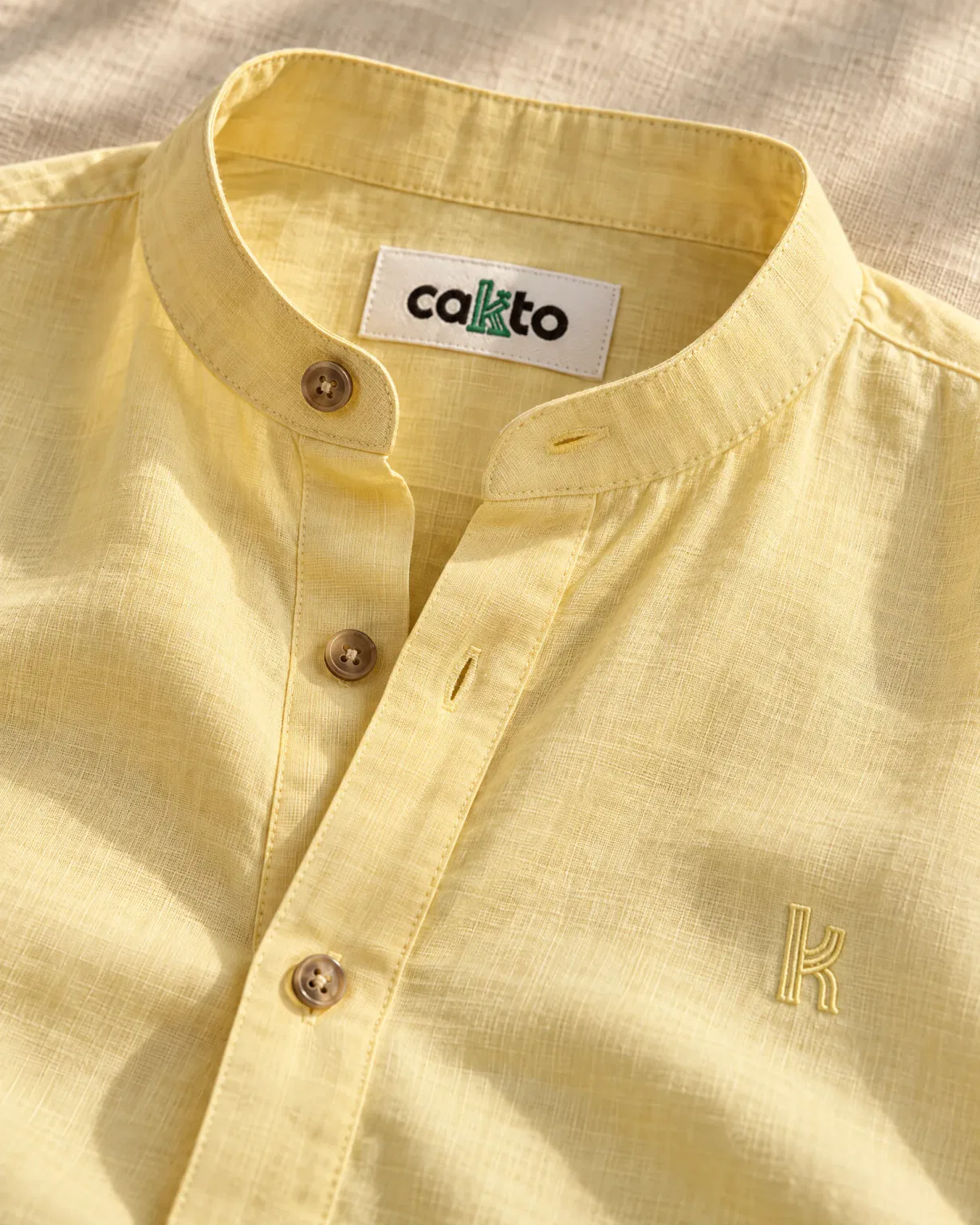 Detalle del cuello, la tela y la etiqueta Cakto de la camisa cuello neru amarilla