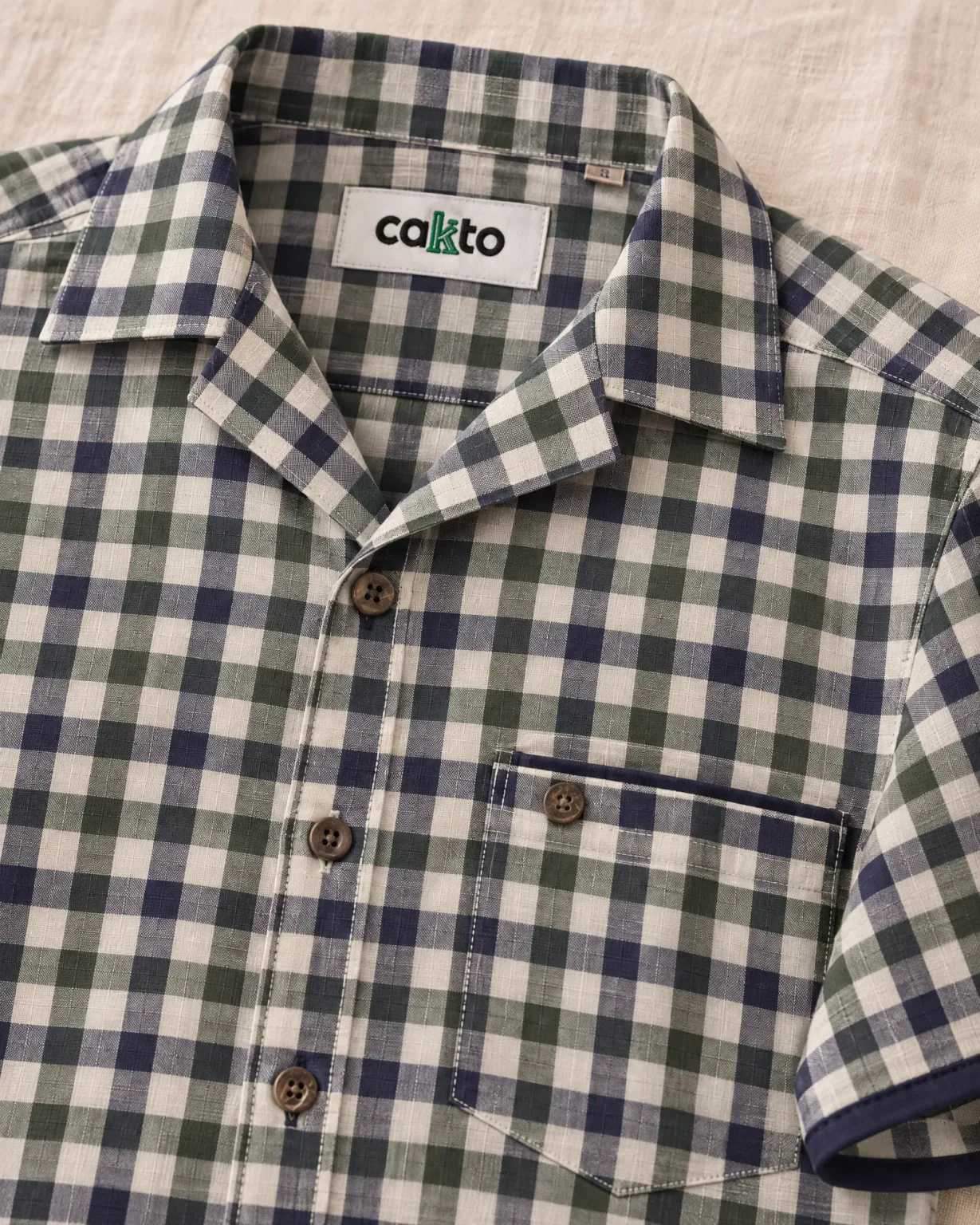 Detalle de los cuadros, el bolsillo y la etiqueta Cakto de la camisa leñadora verde
