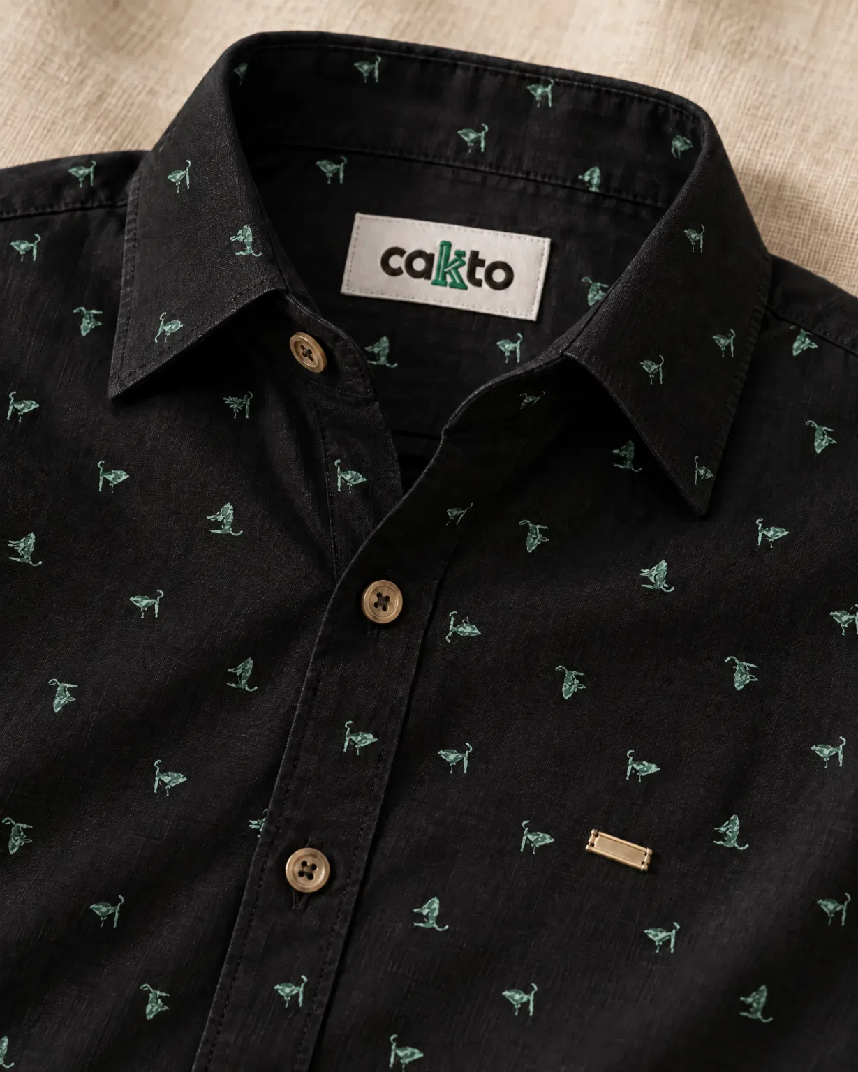 Detalle del estampado de espigas, la plaquita y la etiqueta Cakto de la camisa trigo verde negra