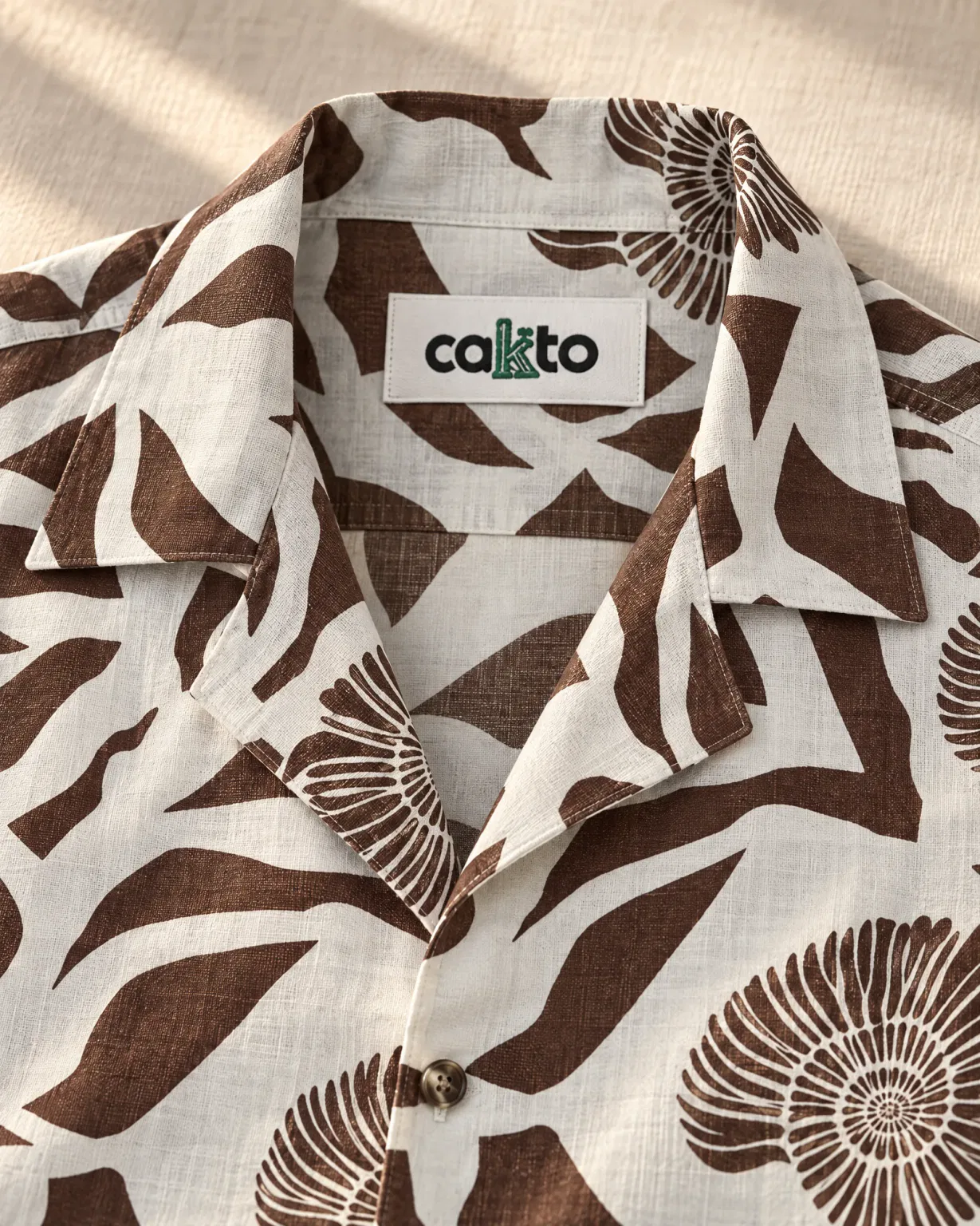 Detalle del estampado, el cuello y la etiqueta Cakto de la camisa caracol café